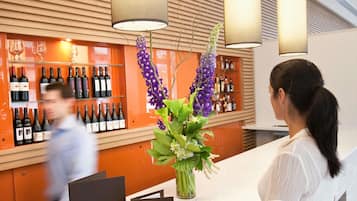 A reception area with a counter, wine bottles, and a vase with flowers.