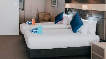 A hotel room with two beds, a headboard, bedside lamps, a nightstand, and a wardrobe.