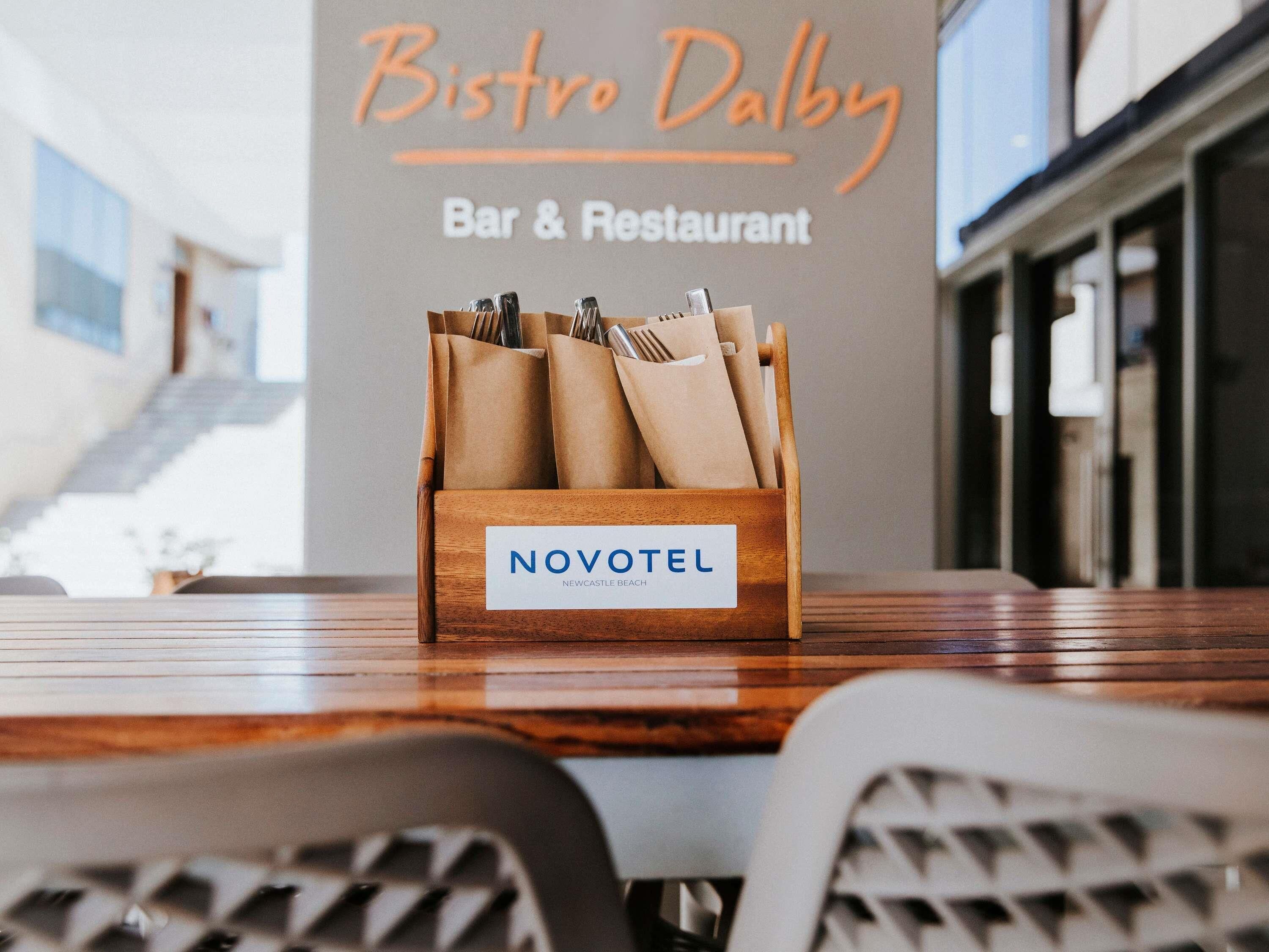 A wooden Novotel sign on a table with a Bistro Dalby sign in the background.