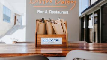 A wooden Novotel sign on a table with a Bistro Dalby sign in the background.