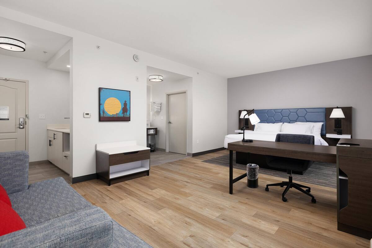 A modern hotel room with a bed, desk, and seating area.