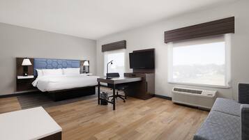 A modern hotel room with a bed, desk, chair, TV, and large windows.