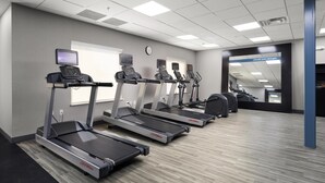 Ein Fitnessraum mit Laufbändern, einer Wanduhr und motivierenden Hinweisschildern.