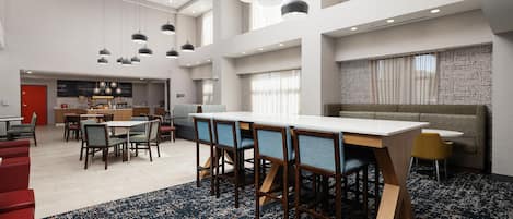 Un amplio vestíbulo de hotel con techo alto, varias zonas de estar y una mesa de comedor central.