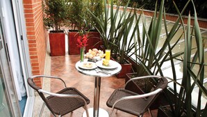 A small outdoor patio with a round table, two wicker chairs, and a potted plant. - Blue Suites Hotel (Bogotá)