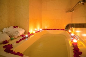 Una bañera con pétalos de rosa y velas, evocando un ambiente romántico.