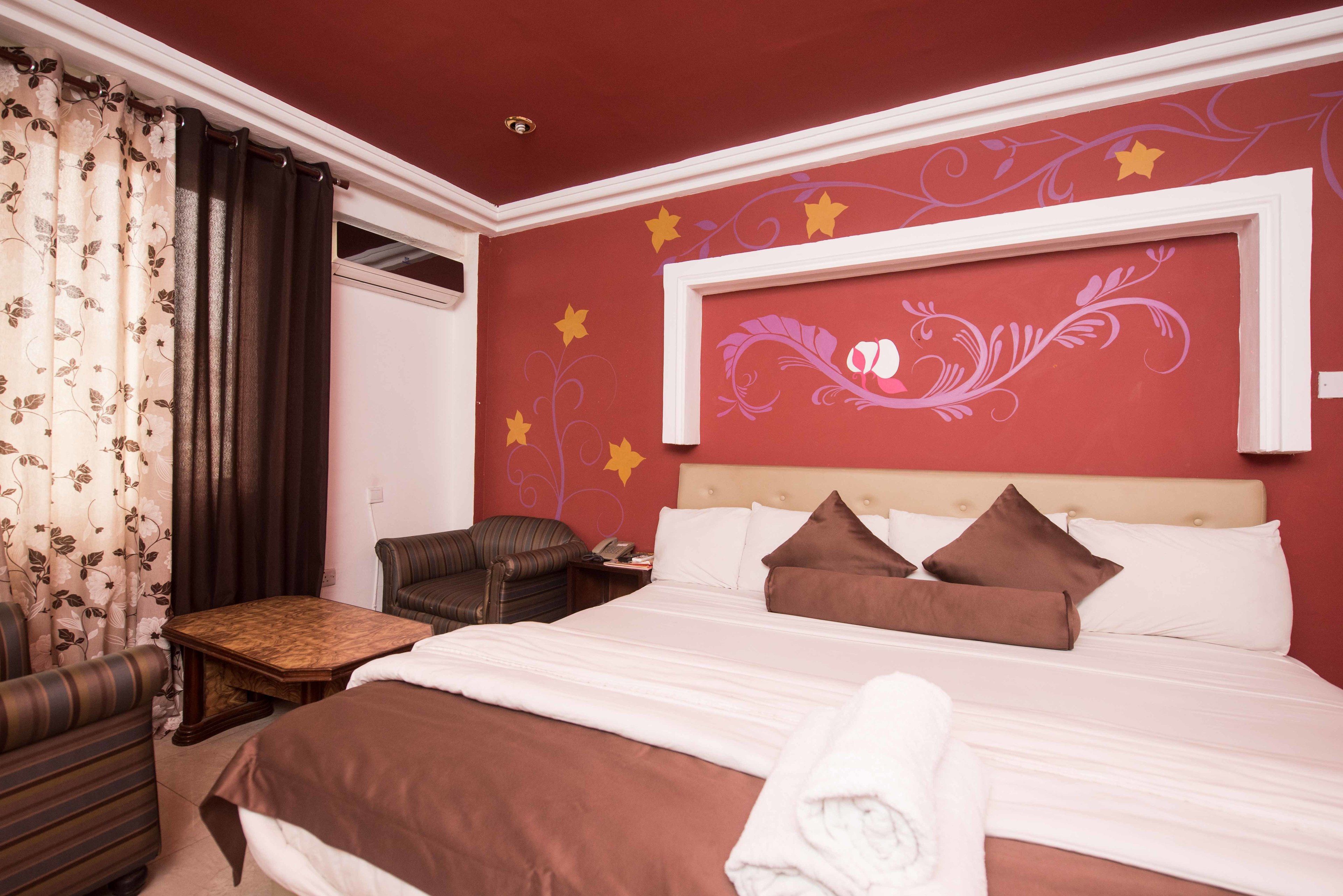 Una habitación de hotel con cama, una silla, una mesita y un adorno en la pared.
