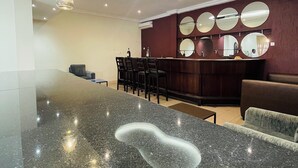 Eine moderne Hotellobby mit einem großen Empfangstresen aus Granit, mehreren Sitzbereichen und zeitgenössischer Pendelleuchten.