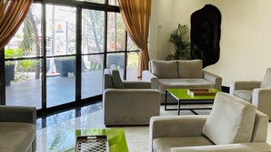 Ein modernes Wohnzimmer mit einer Sofagarnitur, einem Couchtisch und einem großen Fenster mit Vorhängen.