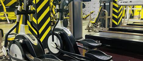 A gym with stationary bikes and treadmills, featuring yellow and black decor.