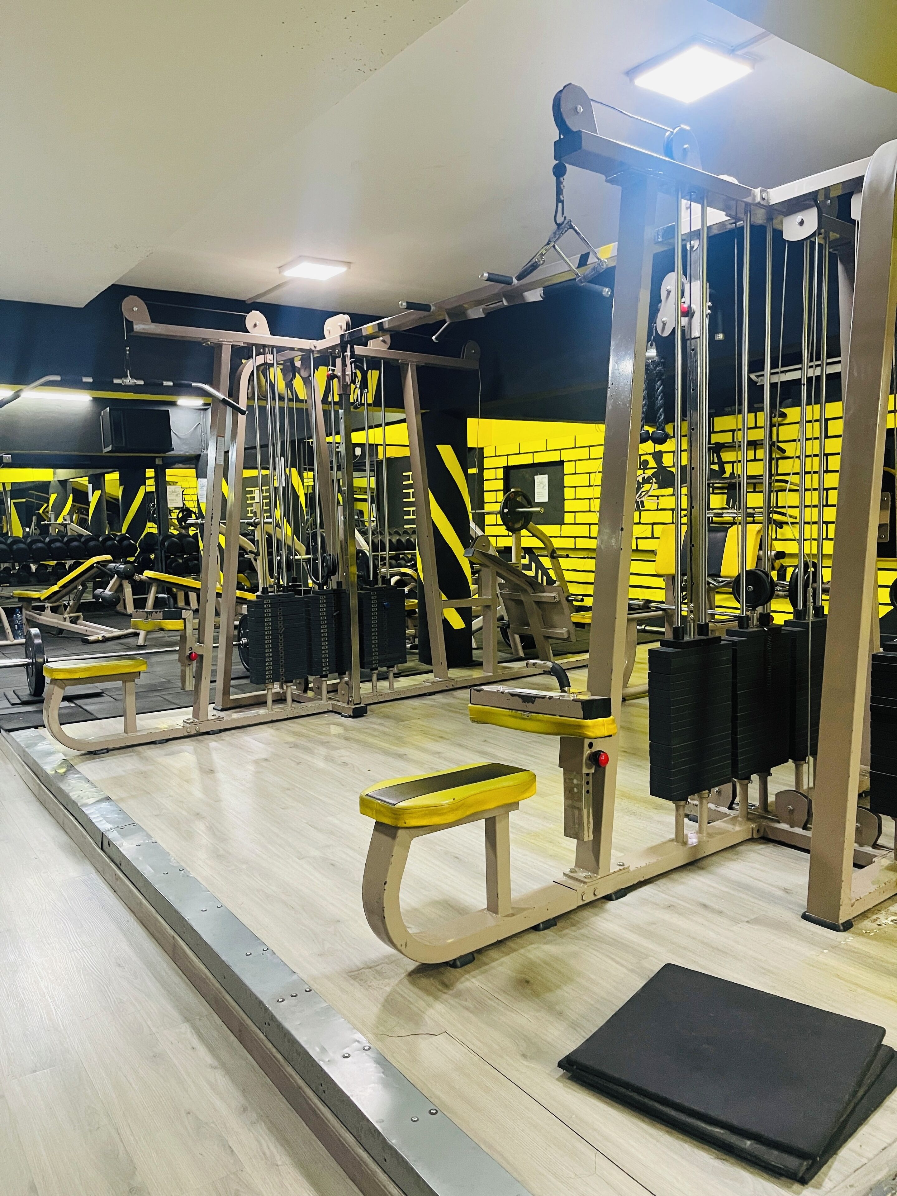 A gym with various exercise equipment, including a bench press, squat rack, and weight benches.