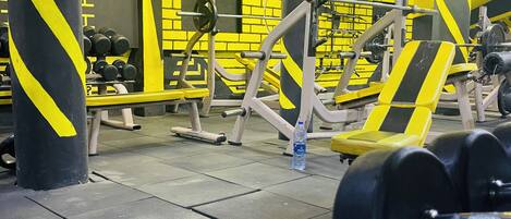 A gym with yellow and black decor, weightlifting equipment, and a bench.