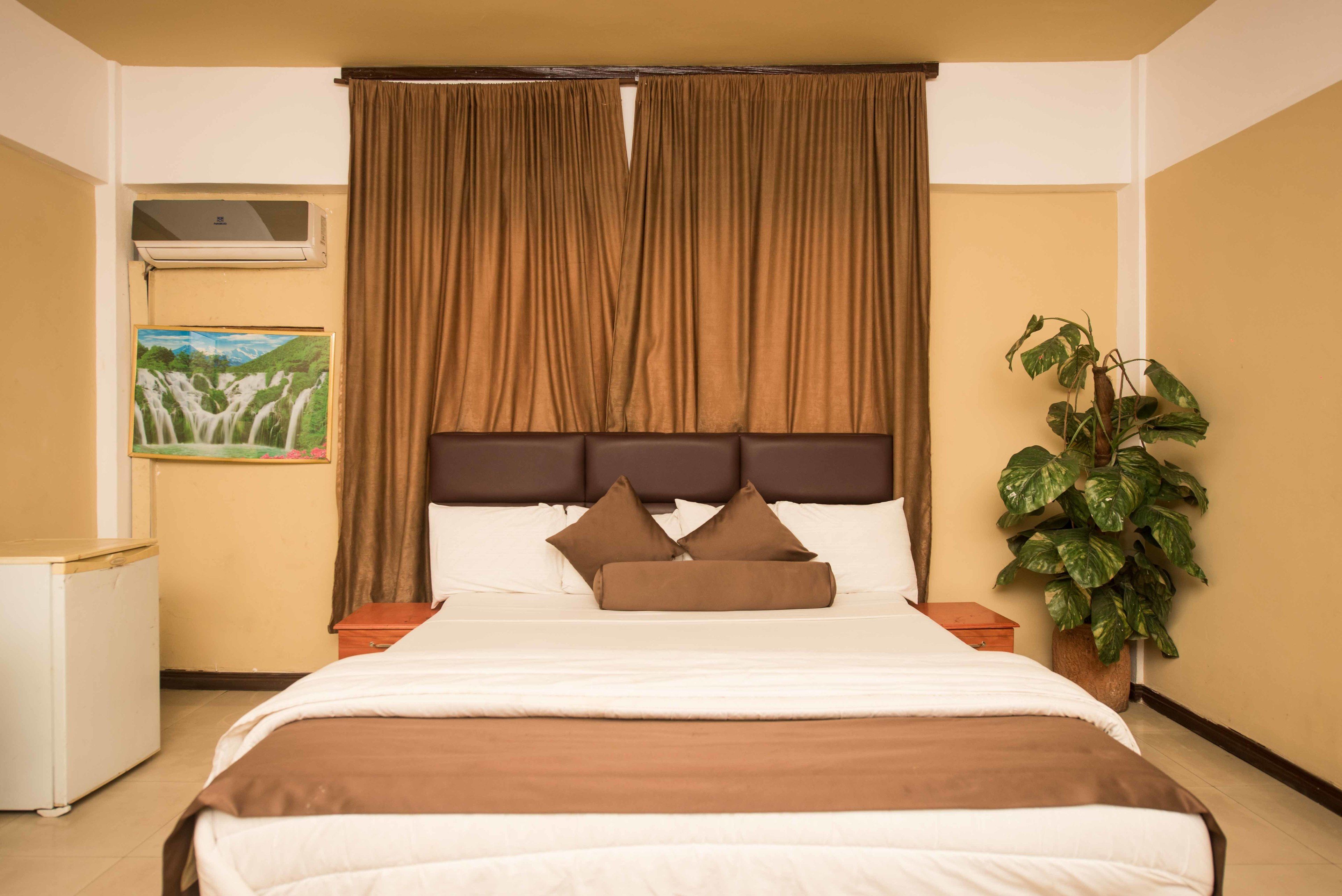 A neatly made bed with brown bedding, a headboard, and two nightstands.