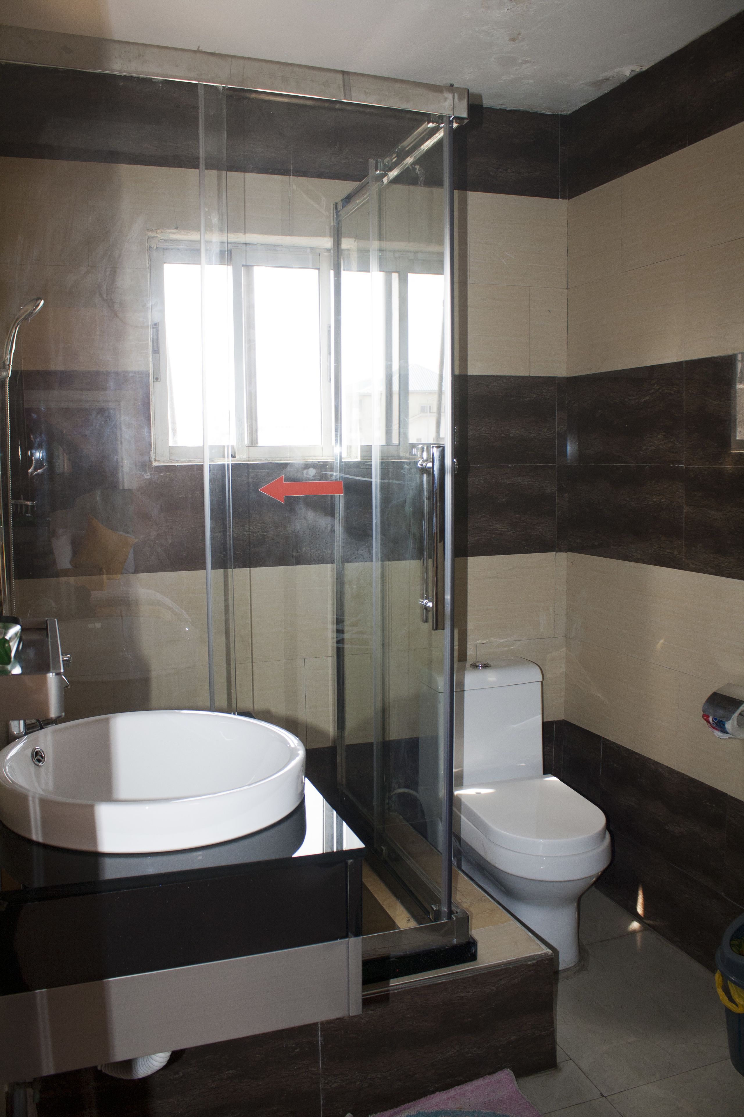 Une salle de bain moderne avec une douche à parois de verre, un lavabo blanc et des toilettes.
