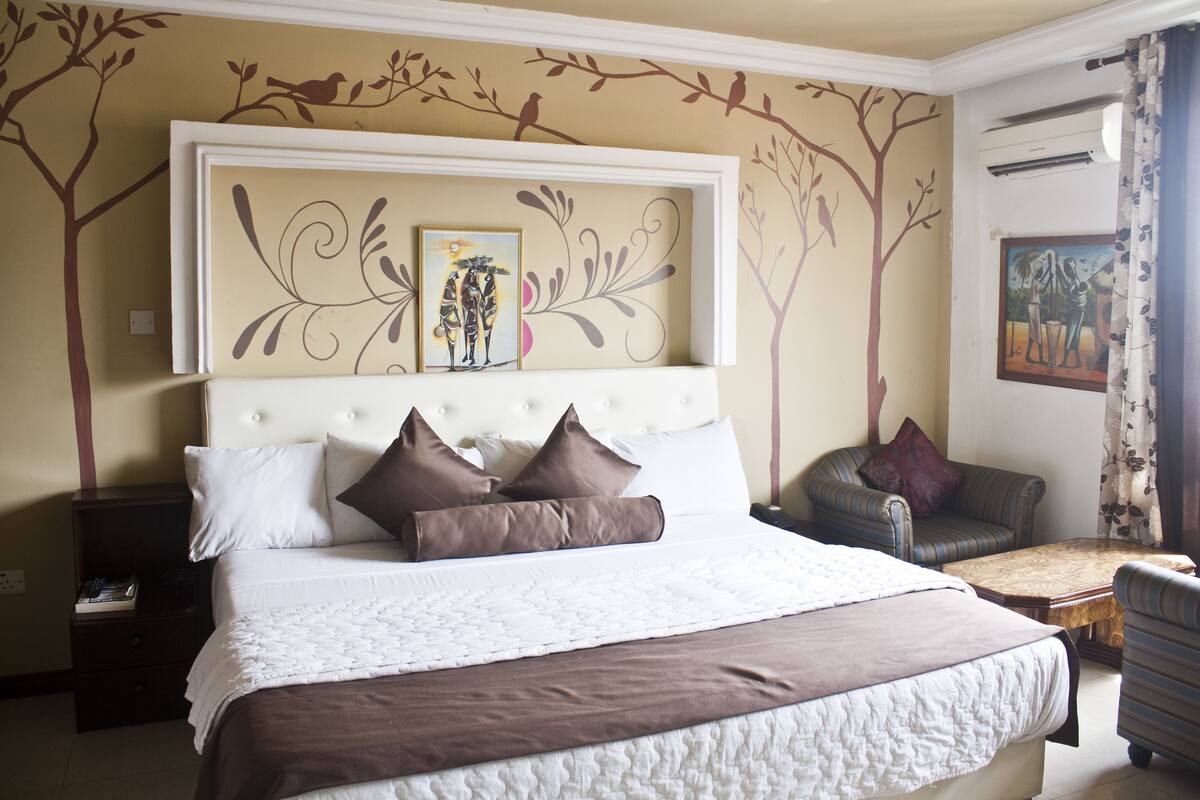Un dormitorio ordenado con una cama grande, un sofá y una pequeña mesa.