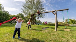 Een speeltuin met een glijbaan, schommels en klimconstructies.