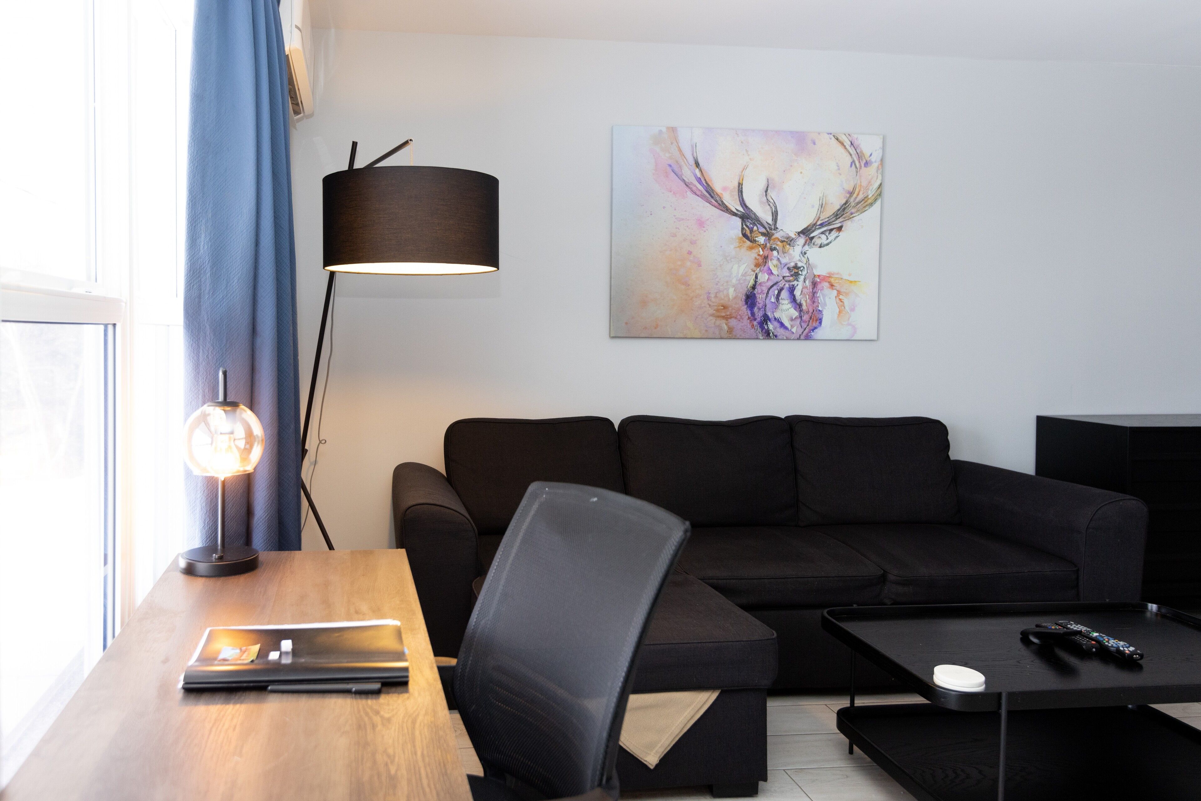 Una sala de estar moderna con un sofá, una mesa de centro, una lámpara y un cuadro en la pared.