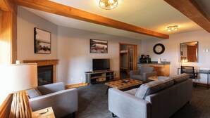 A modern living room with a fireplace, sofa, TV, and wooden beams. - Terrace Suites (Callander)