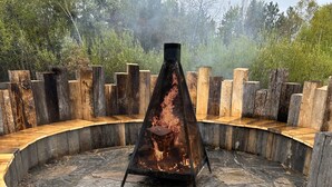 A circular outdoor seating area with a central fire pit surrounded by stone flooring and wooden benches. - Terrace Suites (Callander)