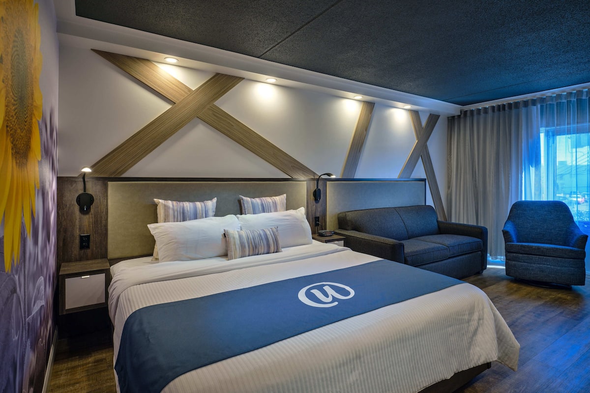 Ein modernes Hotelzimmer mit einem großen Bett, einer Schlafcouch und einem Schreibtisch.