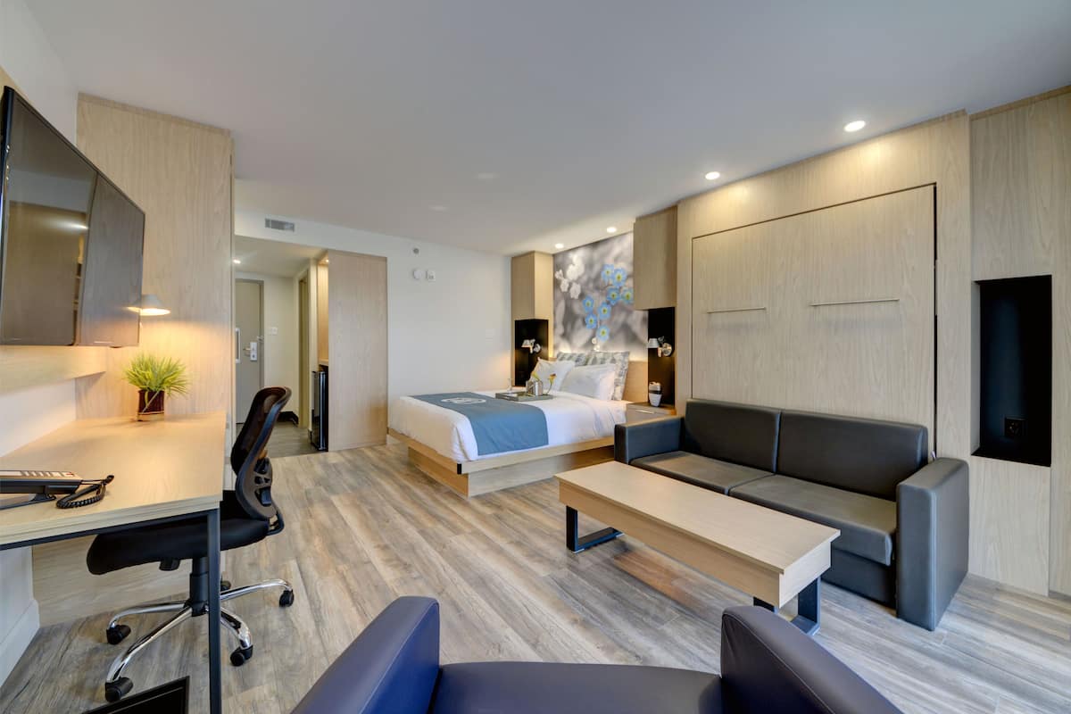 Ein modernes Hotelzimmer mit einem Bett, einer Couch, einem Schreibtisch und einem Sessel.
