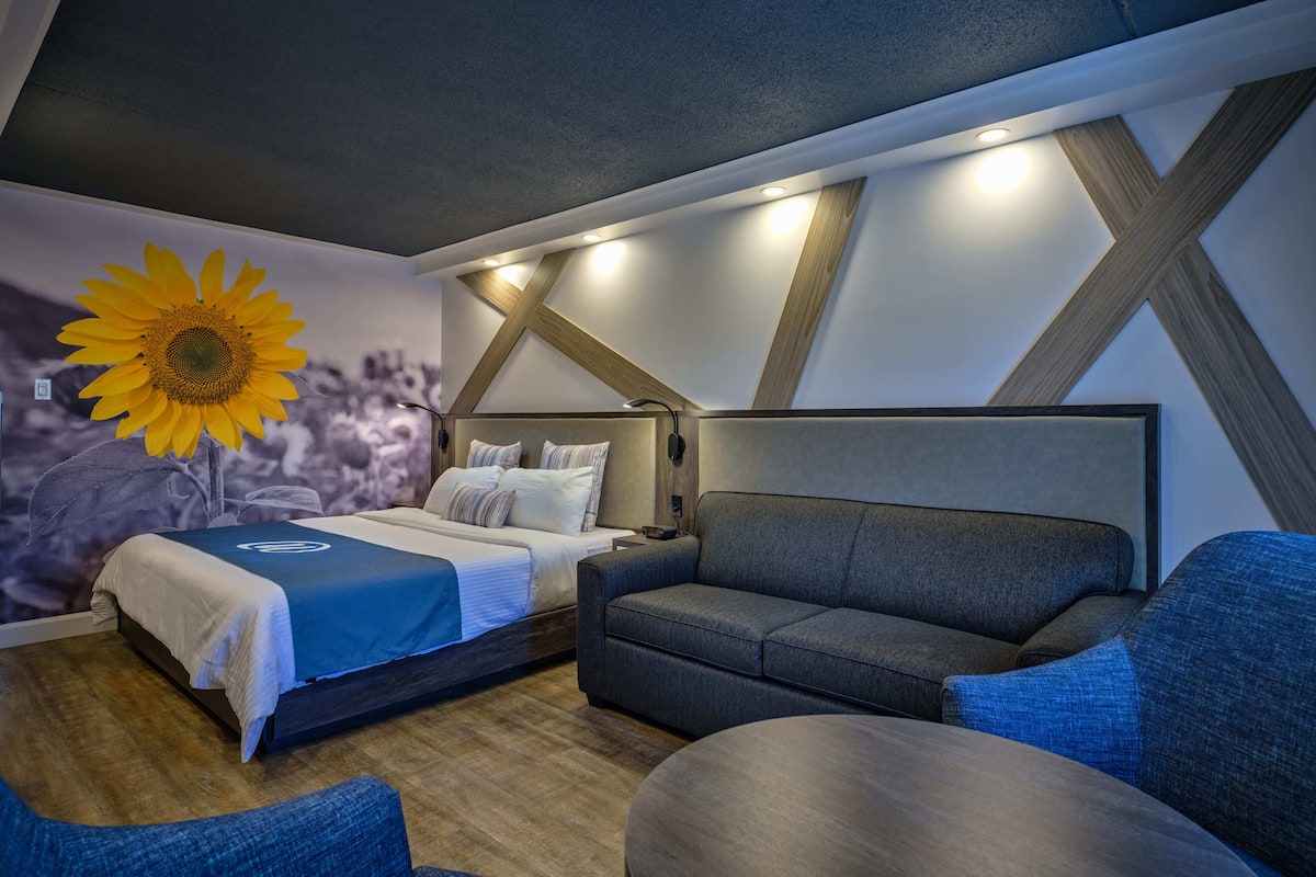 Ein modernes Schlafzimmer mit Bett, einer Couch und einem an der Wand montierten Fernseher.