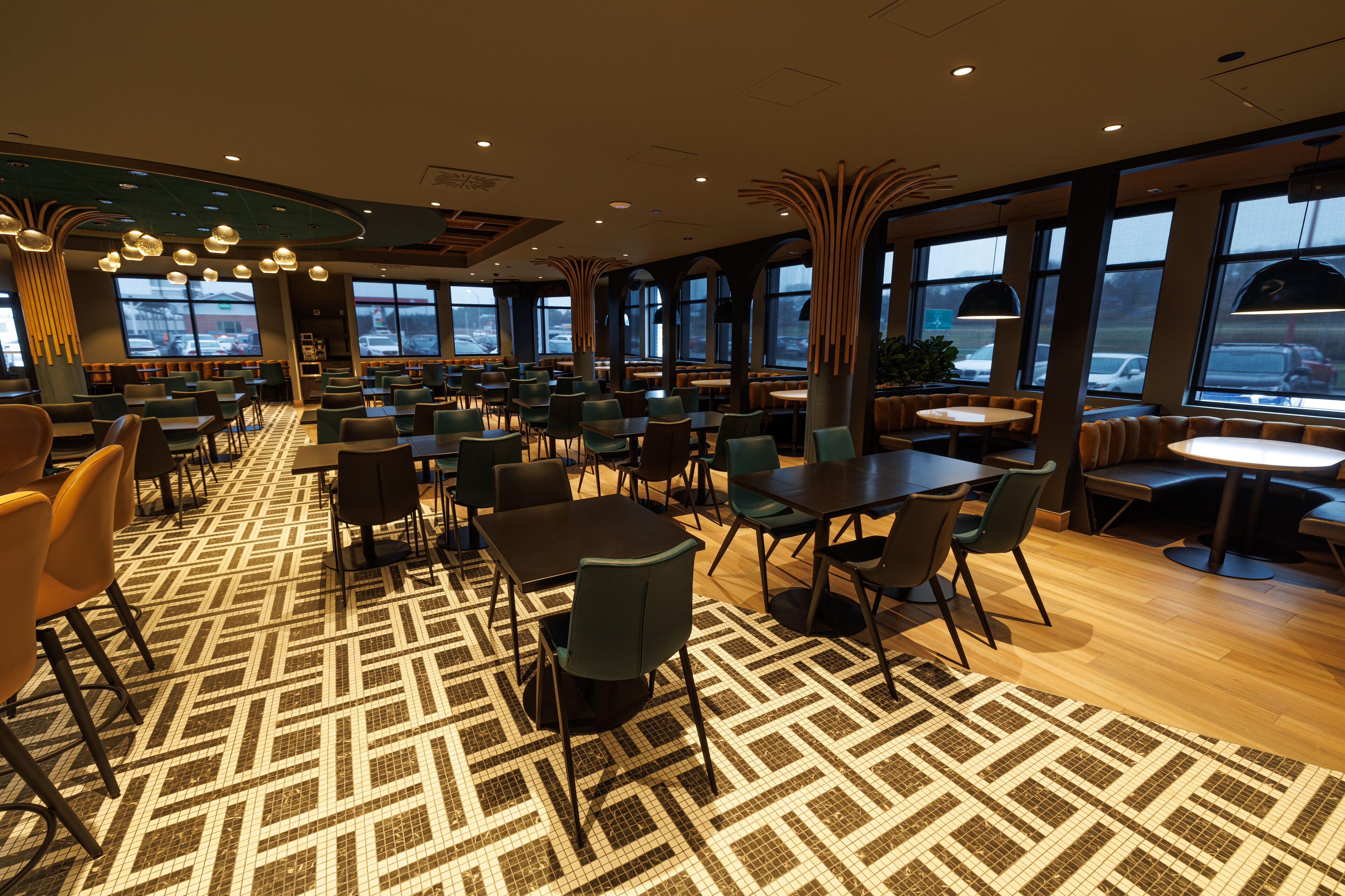 A spacious restaurant with high ceilings, large windows, and a patterned floor.