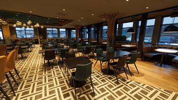 A spacious restaurant with high ceilings, large windows, and a patterned floor.