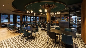 Un restaurant moderne avec des tables et des chaises rondes, un sol à motifs et un plafond au design original.