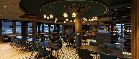 Un restaurante moderno con mesas y sillas redondas, un suelo con diseño y un techo original.