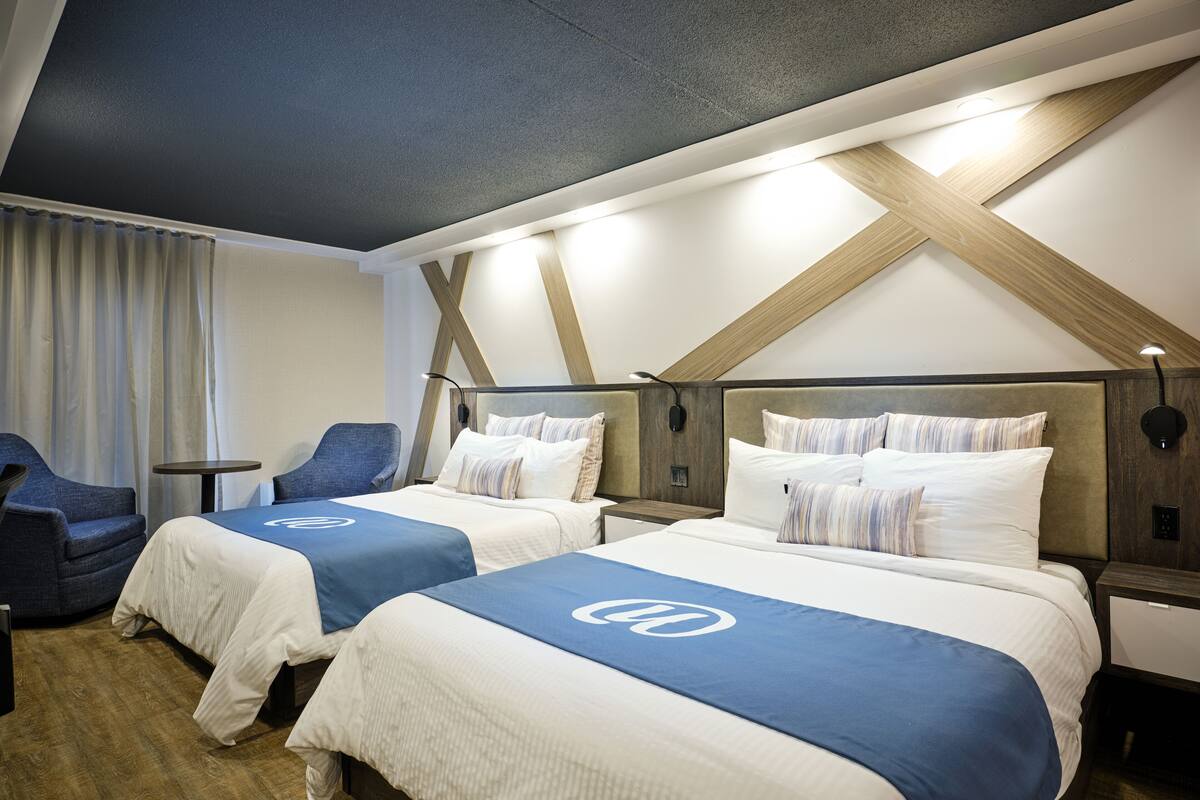 Ein Hotelzimmer mit zwei Betten, einem Schreibtisch und einem Stuhl.