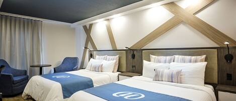 A hotel room with two beds, a desk, and a chair.