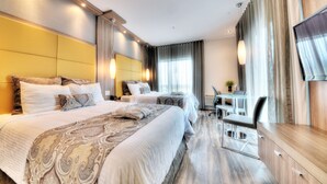 Une chambre d’hôtel avec deux lits, un bureau, une chaise, une télévision et une fenêtre avec des rideaux.