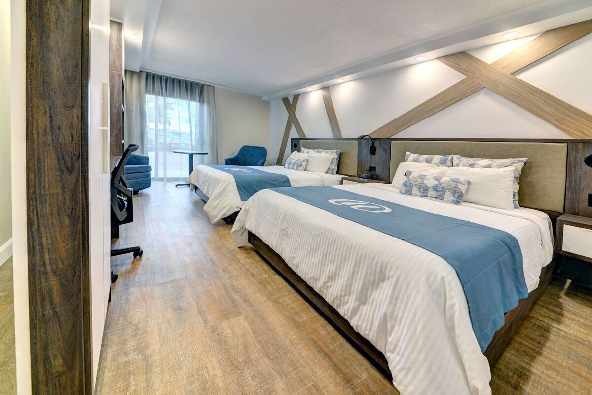 Ein Hotelzimmer mit zwei Betten, einem Schreibtisch und einem Stuhl.