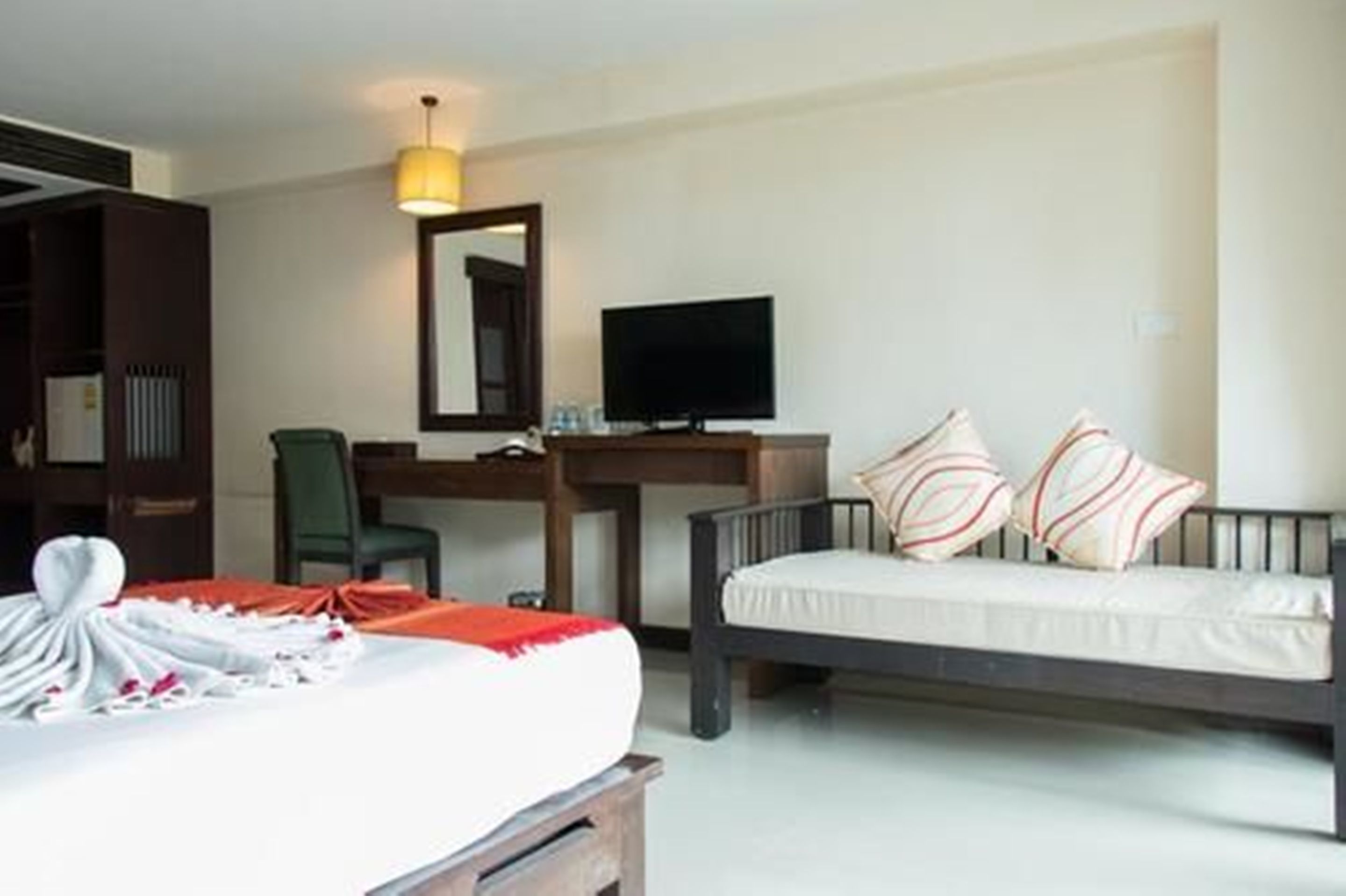 Ein Hotelzimmer mit Bett, Schreibtisch, Stuhl, Fernseher und Kleiderschrank.
