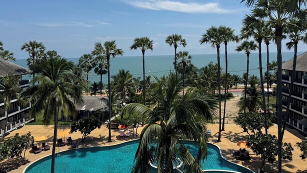A resort with a pool, palm trees, and a view of the ocean. - Pattawia Resort & Spa (Pranburi)