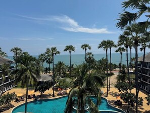 A resort with a pool, palm trees, and a view of the ocean. - Pattawia Resort & Spa (Pranburi)