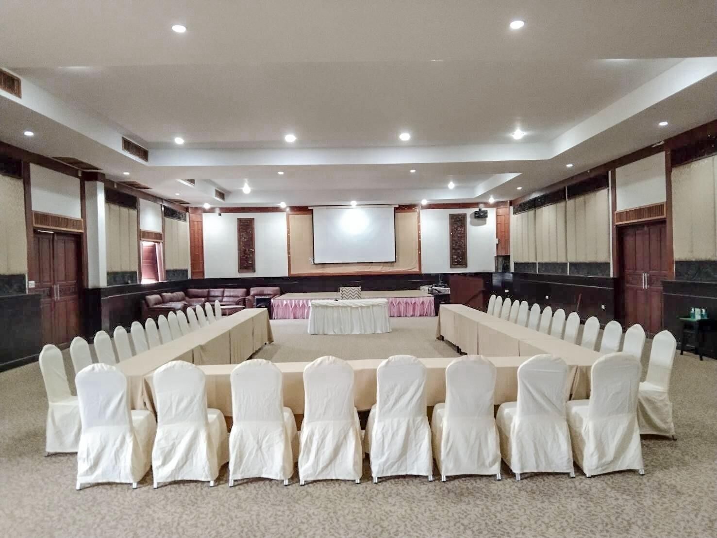 A conference room with a long table and chairs, a screen, and a sofa.