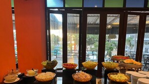 A buffet setup with various food items displayed in bowls and baskets, arranged on a counter with plates and serving utensils. - Pattawia Resort & Spa (Pranburi)