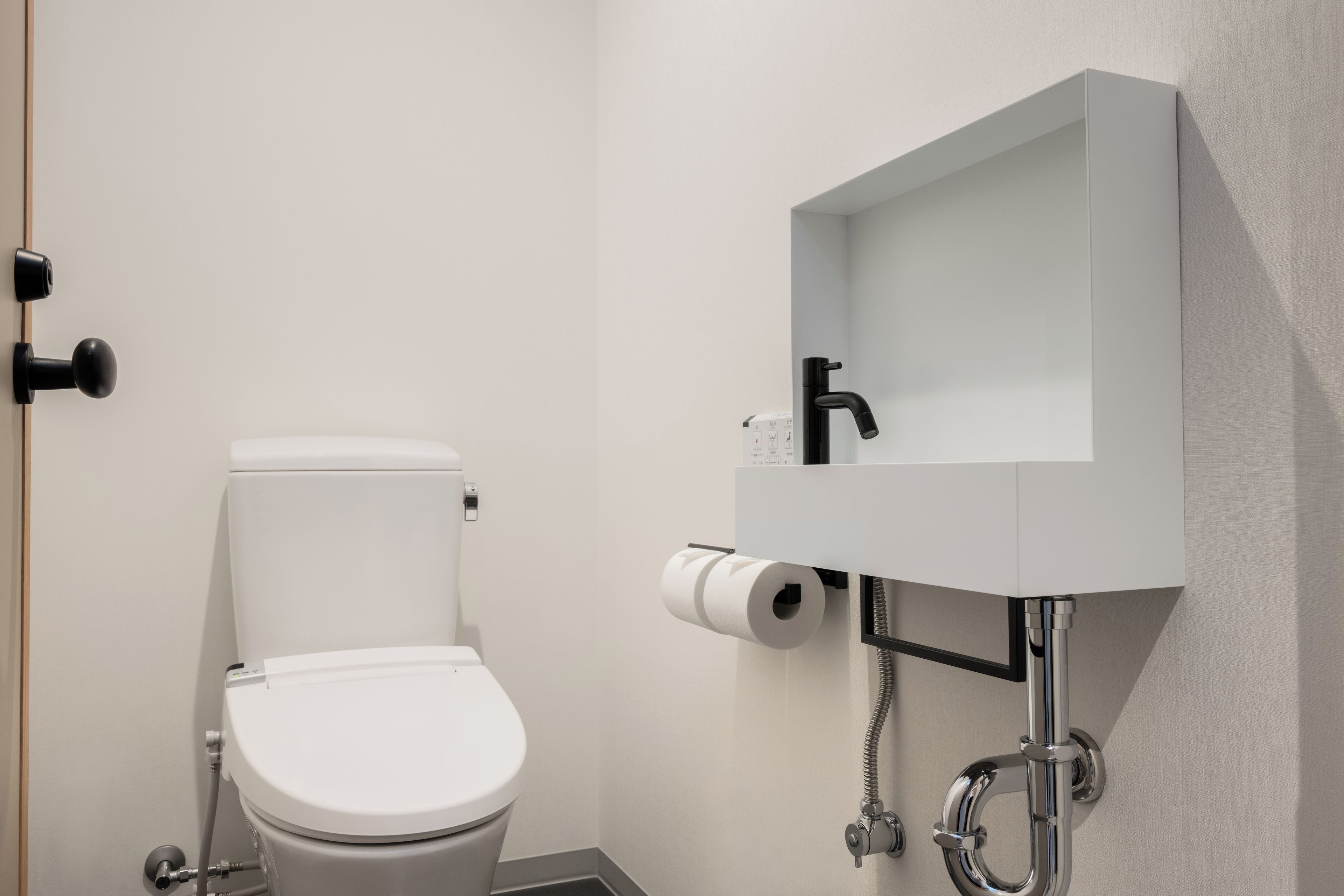 A modern bathroom with a toilet, a sink, and a toilet paper holder.