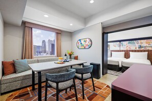 Una habitación de hotel moderna con vista a la ciudad, un área de comedor y una zona de descanso separada.