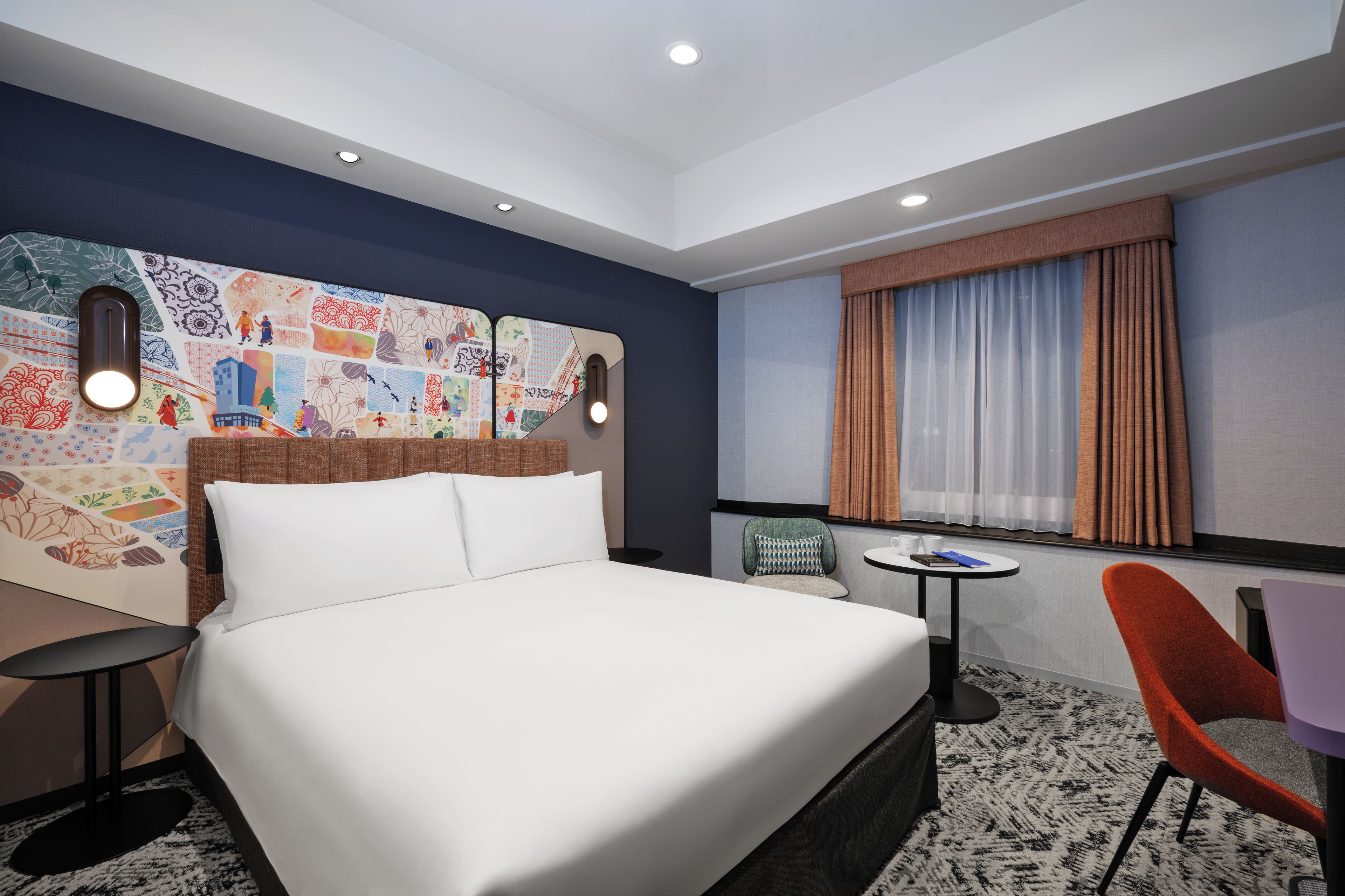 A hotel room with a bed, a chair, a small table, and a decorative wall.