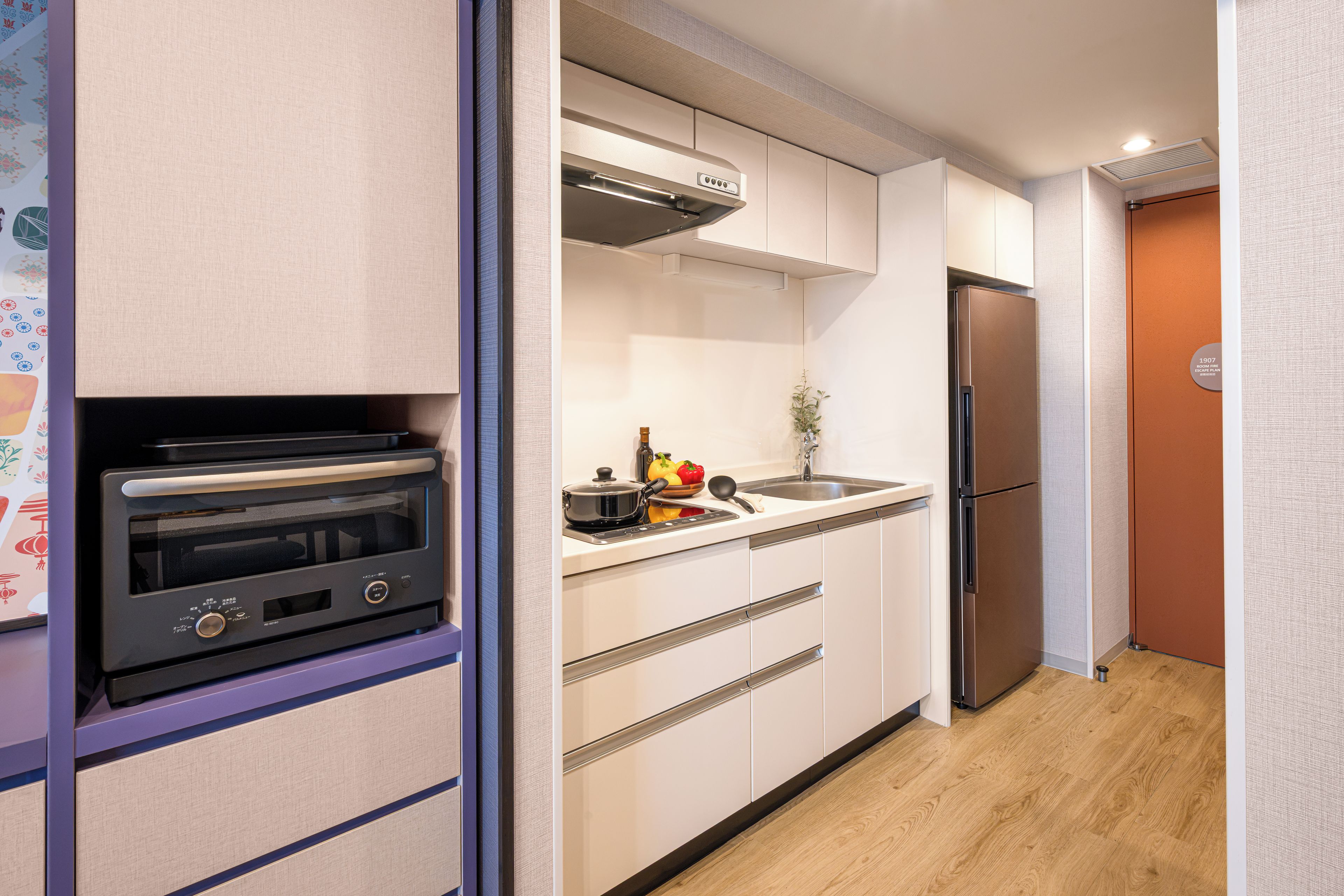 Eine kompakte Küche mit Backofen, Edelstahl-Kühlschrank und Mikrowelle.