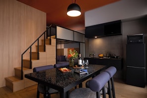 A modern kitchen with a built-in oven, a dining area with a glass-top table, and a staircase leading to an upper level.