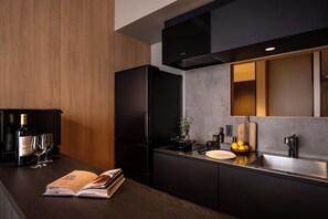A modern kitchen with a dark refrigerator, a wooden countertop, and a mirror above the sink.