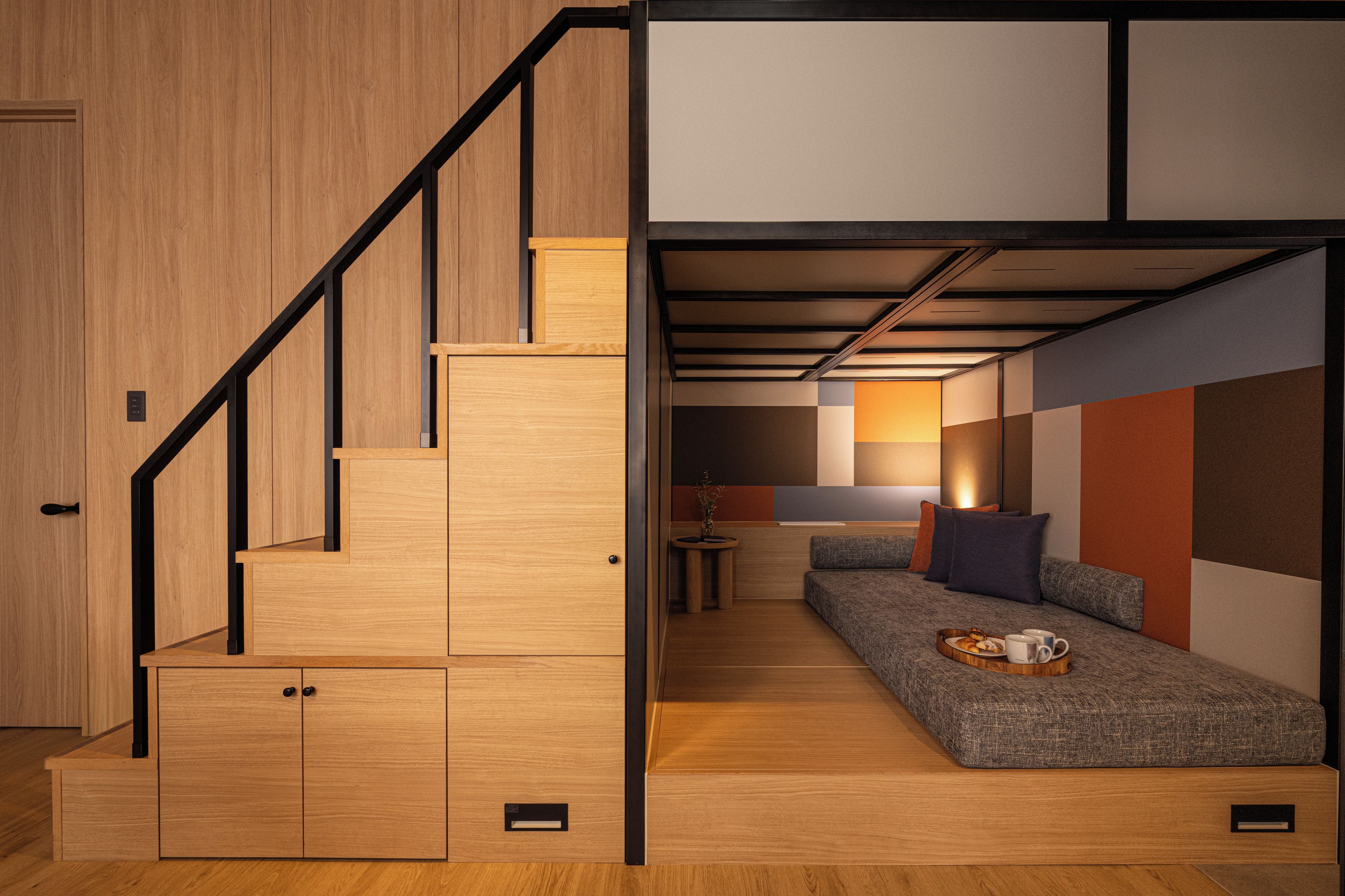 Ein gemütlicher, kompakter Wohnraum mit einer Holztreppe, einer Couch und einem kleinen Tisch mit einer Speiseplatte.
