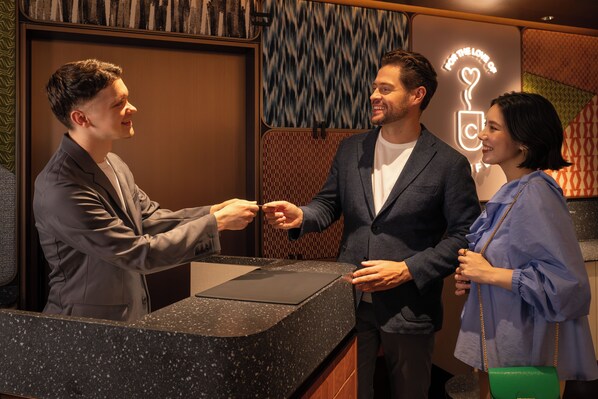 A reception desk with a man and two women standing beside it.