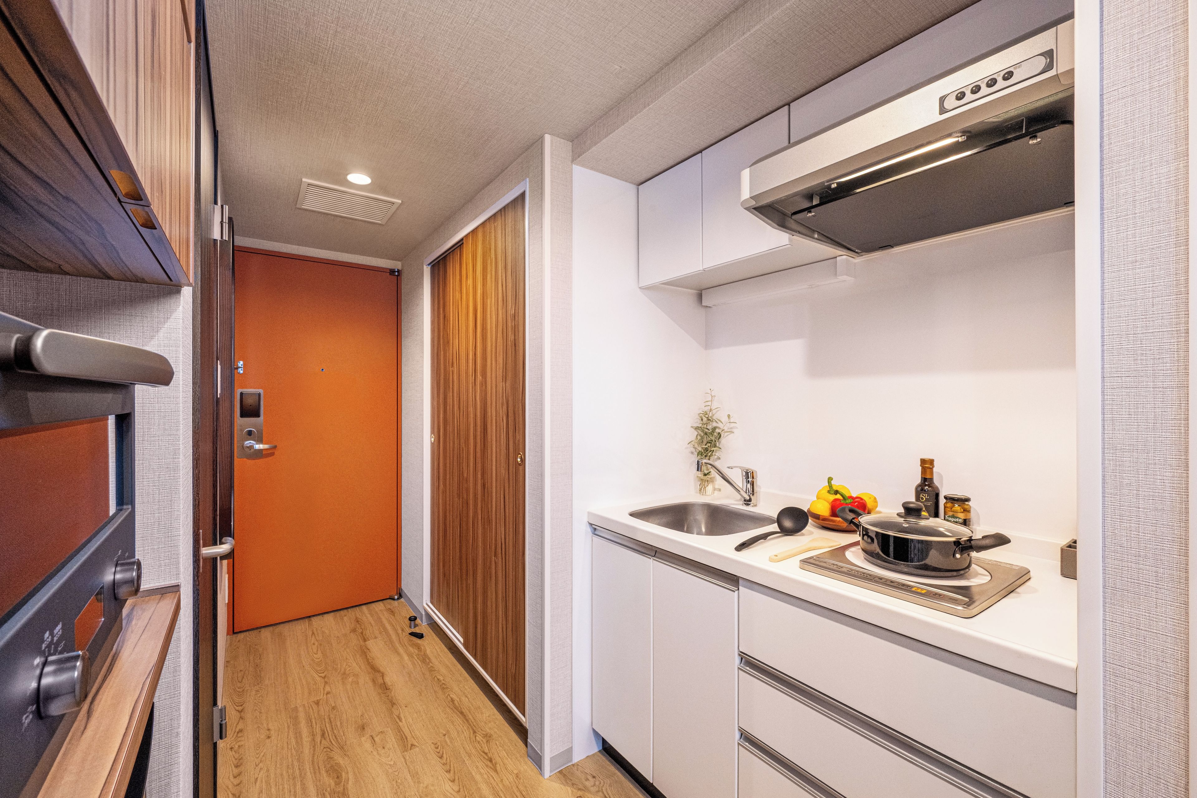 A compact kitchen with a built-in stove, a sink, and a wooden door leading to another room.