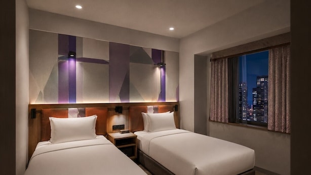 A hotel room with two beds, a nightstand, and a large window with a city view. - Citadines North Shinjuku Tokyo (Tokyo)