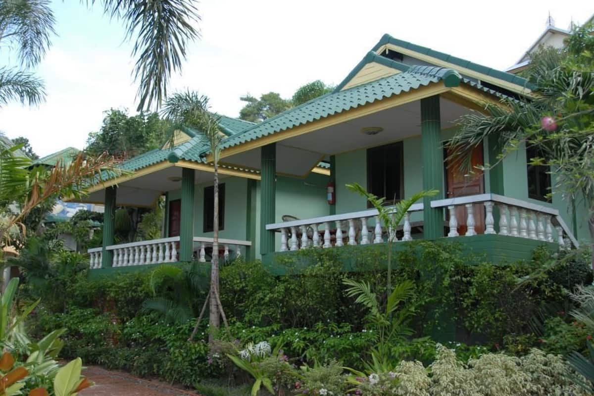 A two-story building with a green and white color scheme, featuring a balcony with white balustrades.